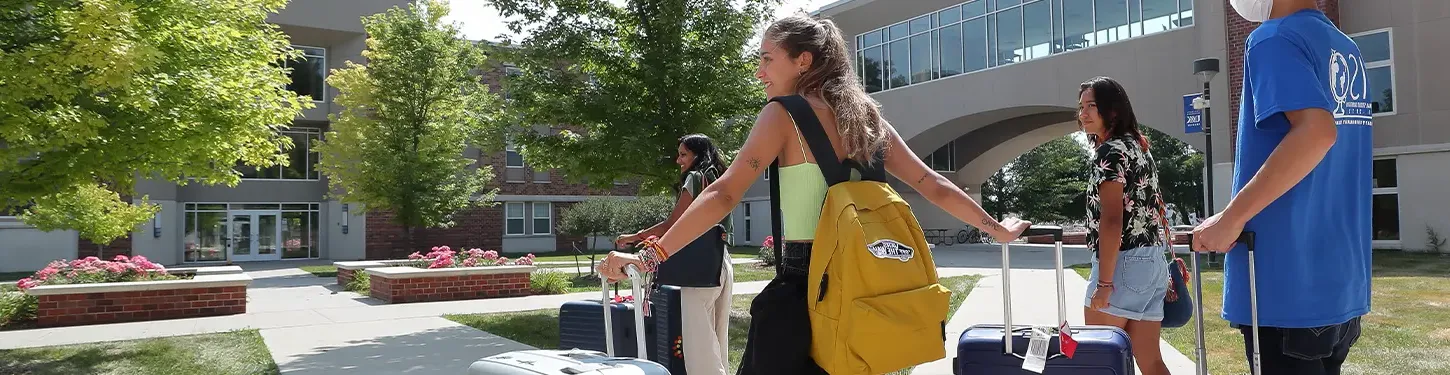 students carrying suitcases across campus